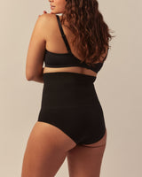 oman wearing a black high-waisted sculpting brief with light to medium support, designed for gentle compression, tummy smoothing, and a seamless, comfortable fit.